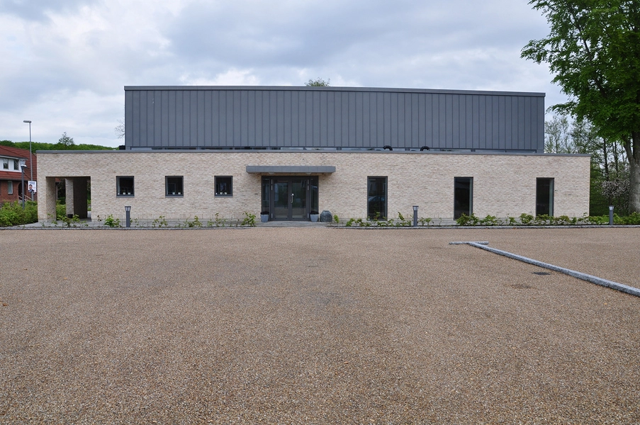 Kirkecenter Hinnerup Bygningen set fra vejen, med parkeringsplads i forgrunden