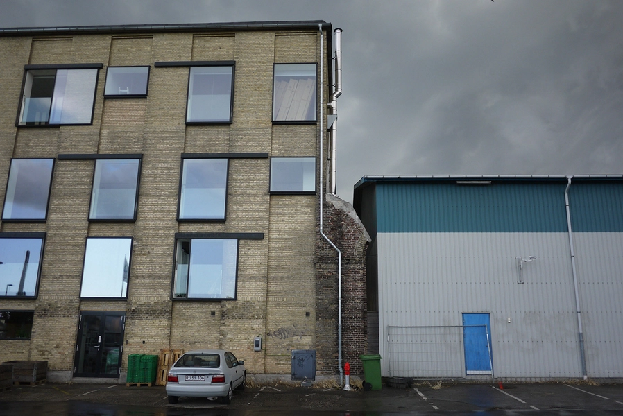 Refshaleøens Værkstedsmagasin og Amass restaurant Facadeudsnit; nye vinduer, murrest fra den gamle smedje, moderne lagerbygning