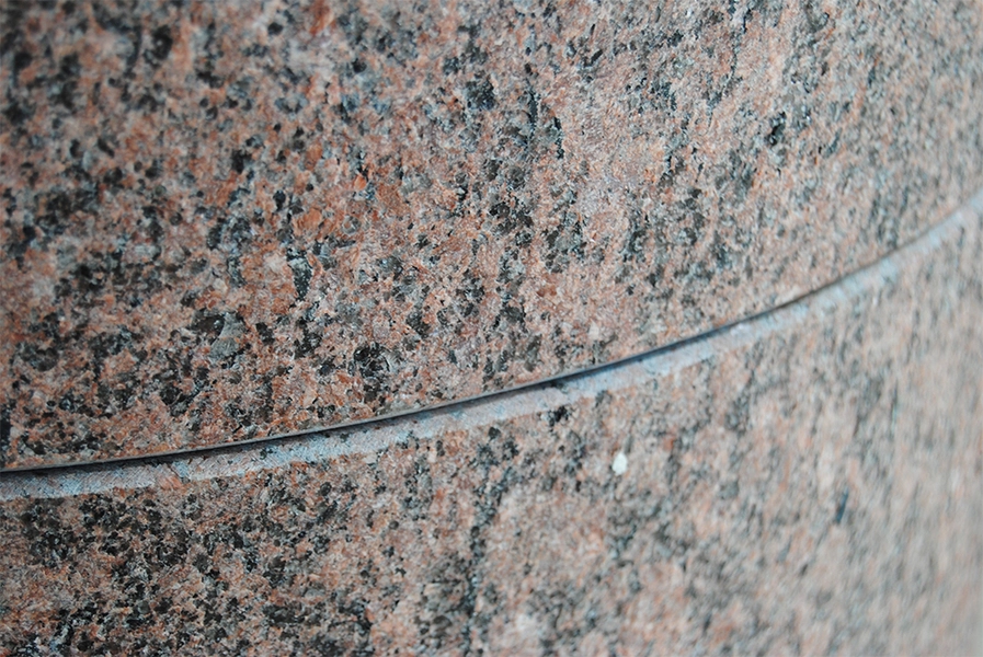 Helligtrekongers Kirke Detalje fra døbefond. Både alter og døbefond er af rød venga-granit fra Sverige